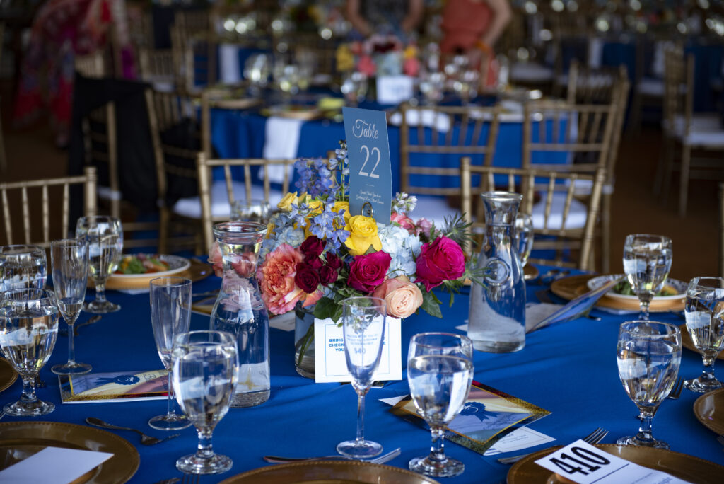 a table with a blue table cloth and gold place settings