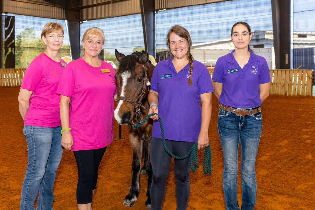 a group of women standing next to a horse
