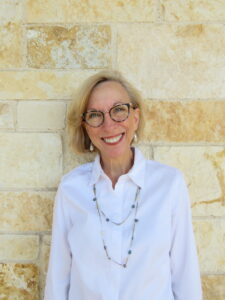 woman wearing glasses standing in front of a brick wall