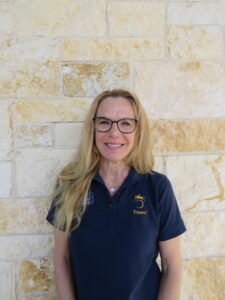 woman wearing glasses standing in front of a stone wall