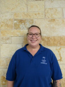 woman in a blue shirt standing in front of a stone wall