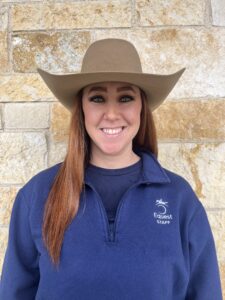 woman wearing a cowboy hat standing in front of a brick wall