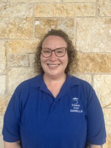 woman in a blue shirt standing in front of a stone wall