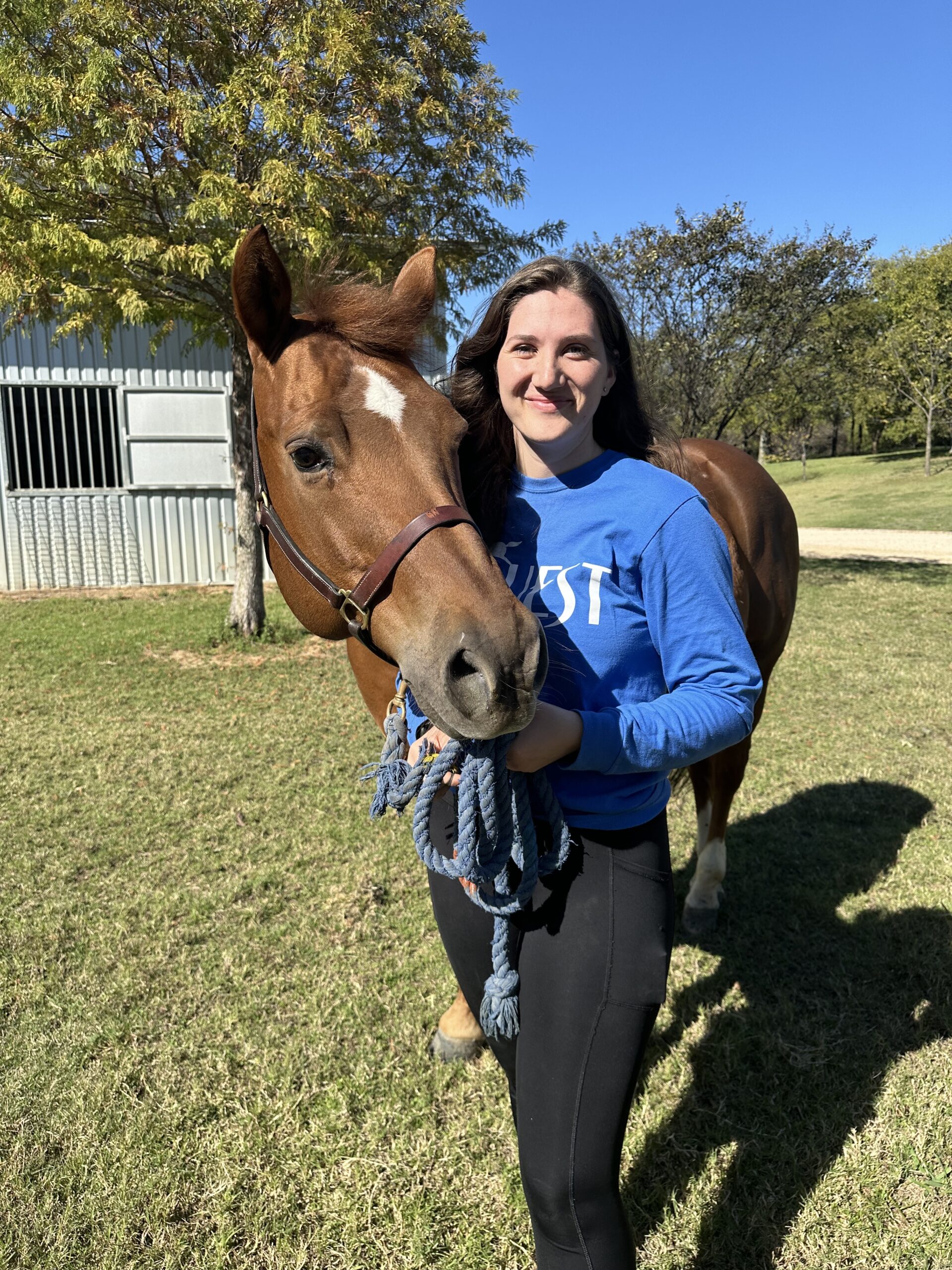 11.2024 EOM Michaela McKinney woman in a blue shirt is holding a brown horse